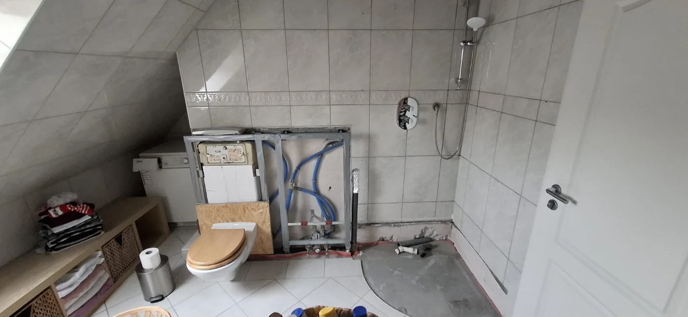 Übernommener Zustand: Teilweise offener WC-Vorwandbereich und unfertige Dusche im Dachgeschoss.